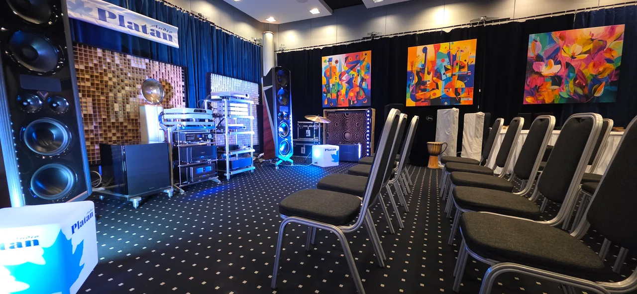 Large canvas prints bringing colour to a listening room with speakers and rows of chairs.