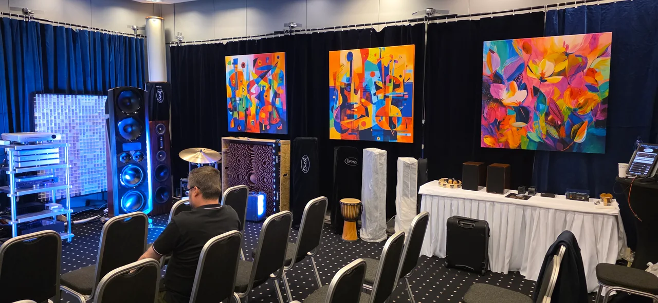 Three colourful floral and music-inspired canvas prints displayed above audio equipment at a customer’s exhibition.